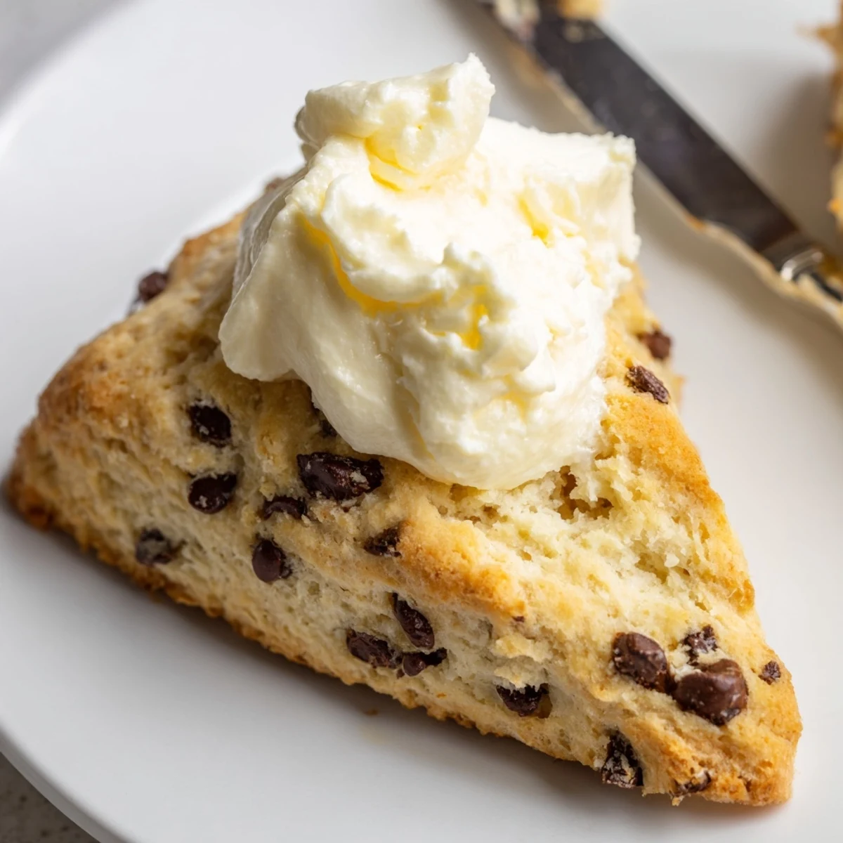 Freshly baked Chocolate Chip Scones with Clotted Cream on a rustic table, perfect for an afternoon tea treat.