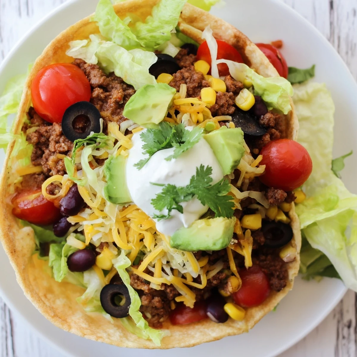 A hearty Beef Taco Salad with Shell loaded with fresh avocado, sour cream, and vibrant salsa.