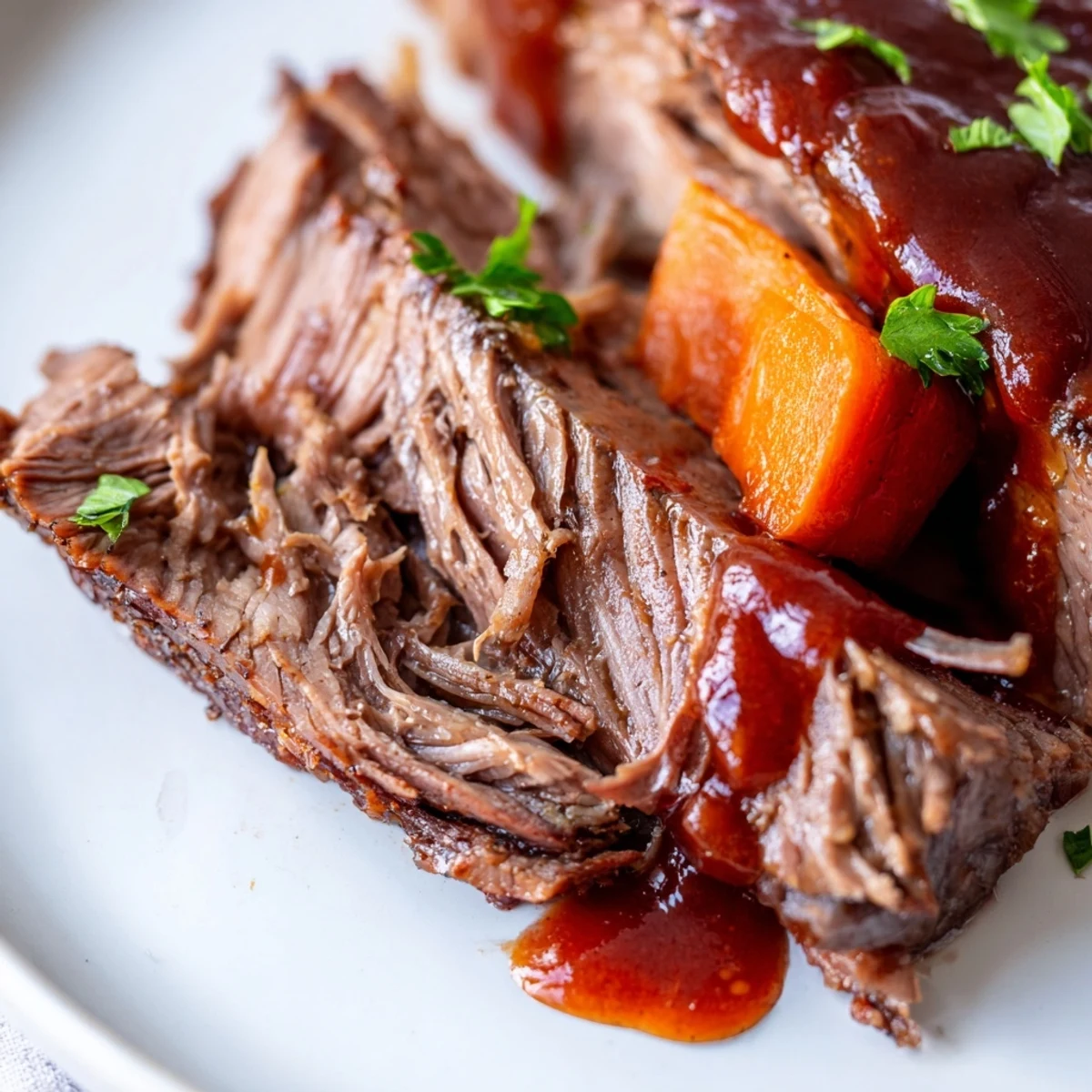 Sliced slow cooker beef brisket on a platter with roasted carrots and onions, drizzled with glossy savory sauce and fresh parsley garnish.