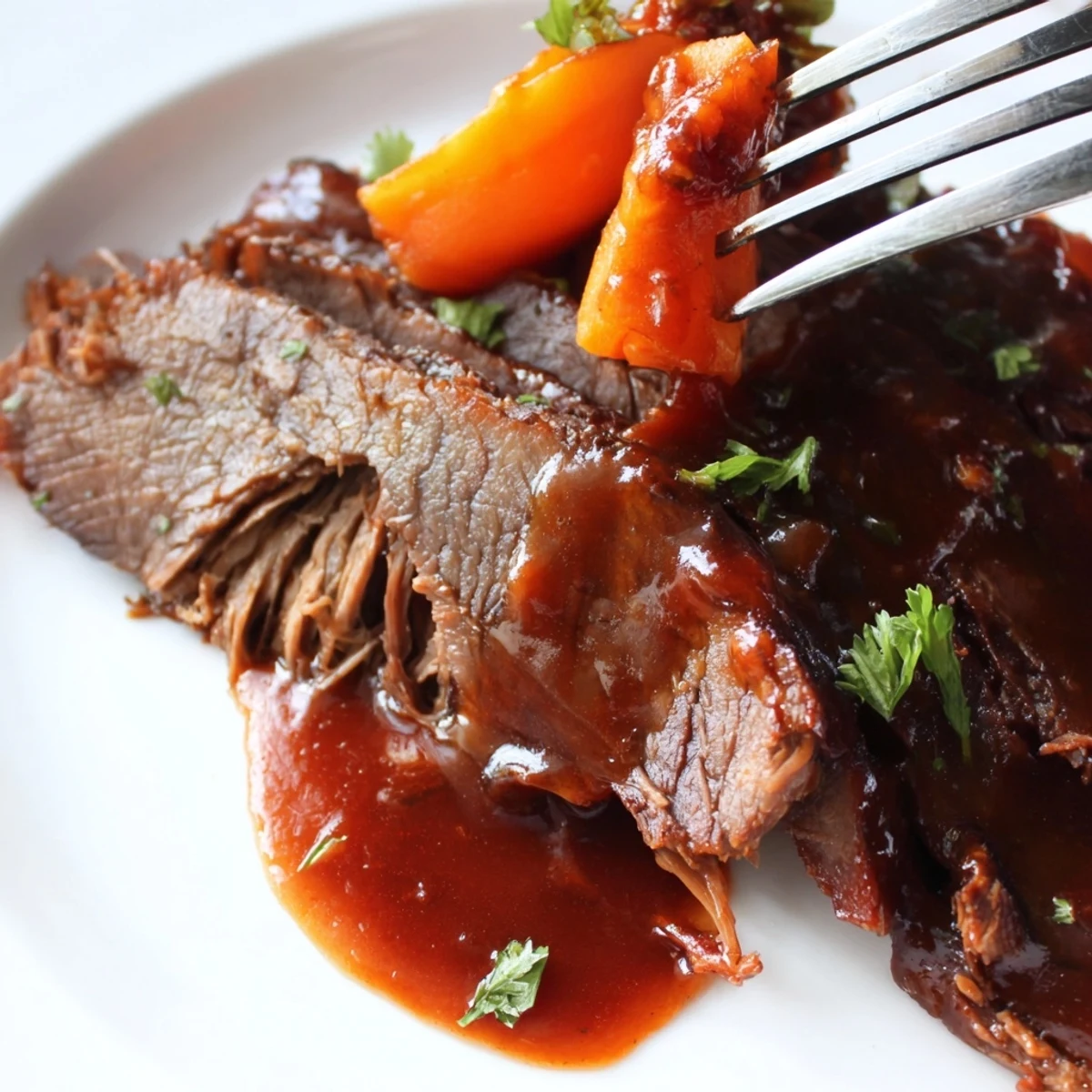 Tender slow cooker beef brisket being pulled apart with forks next to soft carrots in rich, reduced juices and garlic aromatics.