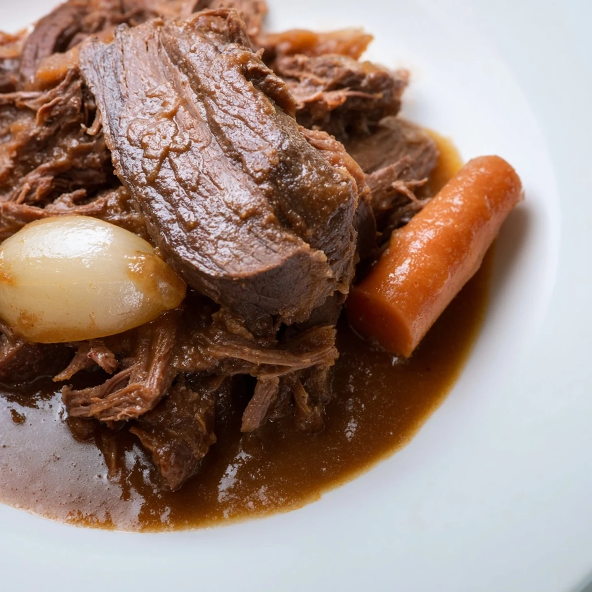 Golden-brown Slow Cooker Roast Beef with Gravy on a platter, surrounded by soft carrots and onions with rich pan juices.