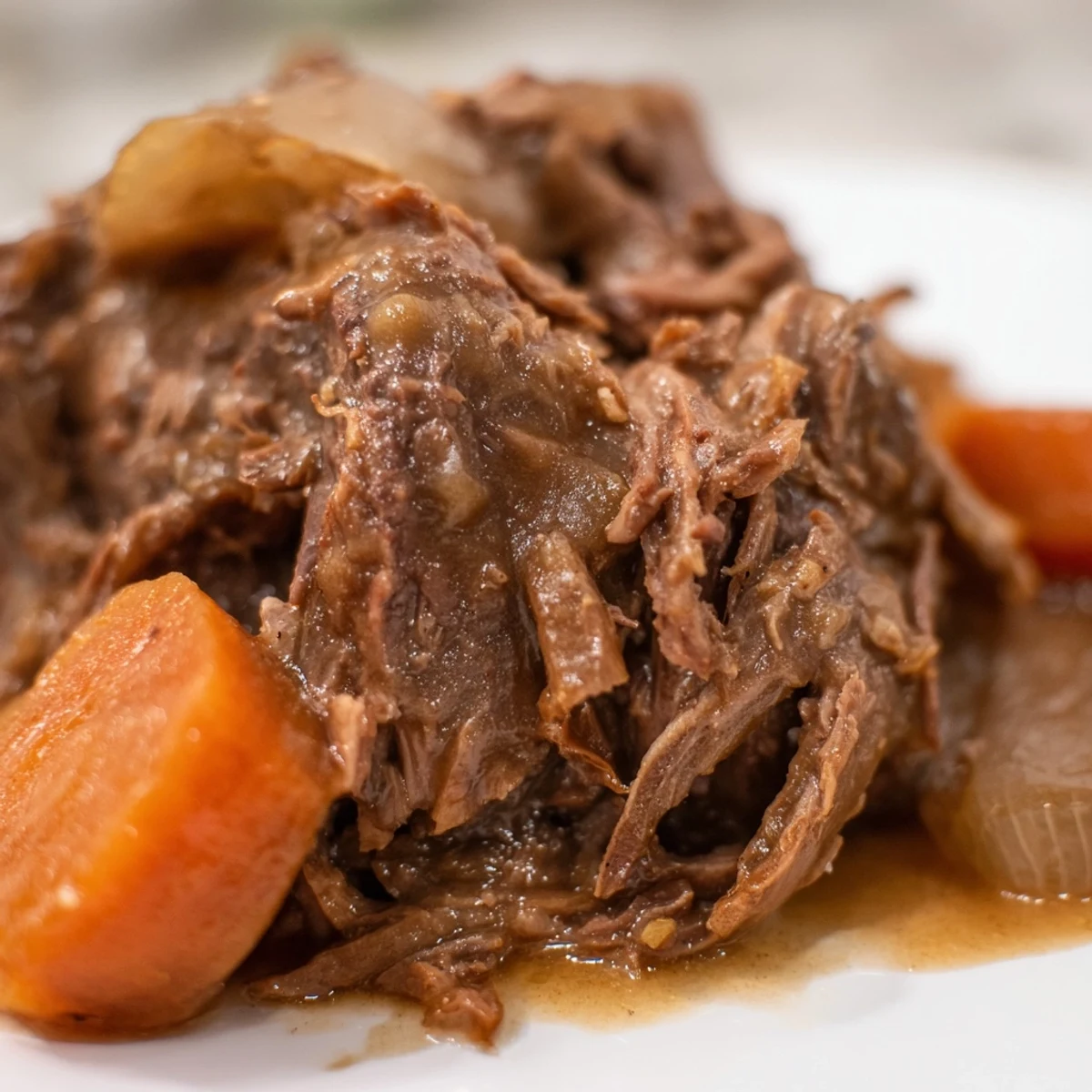 Shredded Slow Cooker Roast Beef with Gravy next to roasted carrots, a rustic meal perfect for busy weeknight dinners.