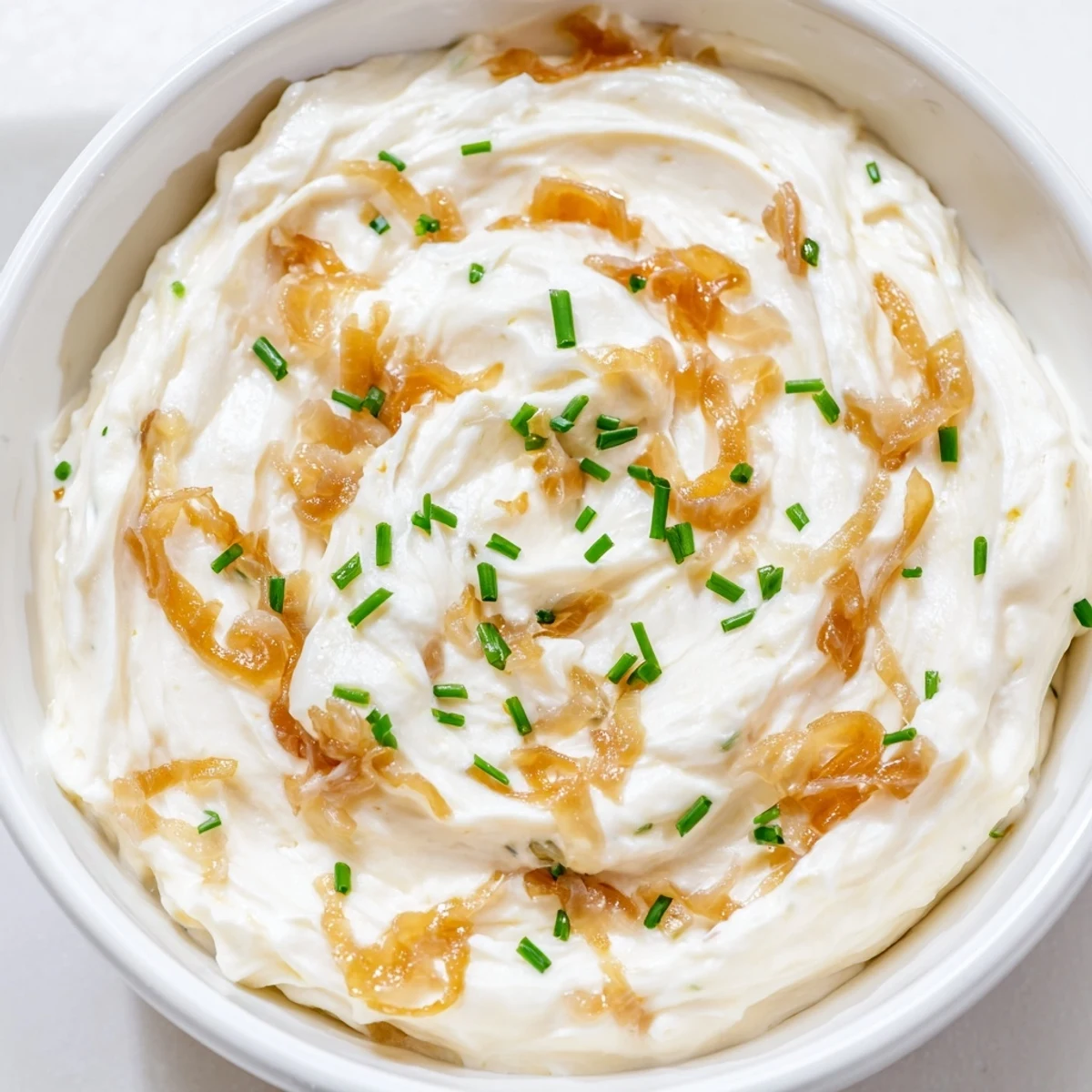 Creamy Game Day Onion Dip with golden caramelized onions, served with crunchy chips and fresh vegetables.