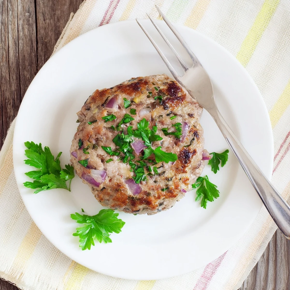 Golden-brown turkey brunch burger patty sizzling in a skillet, seasoned with herbs and garlic for a hearty, high-protein breakfast or lunch.