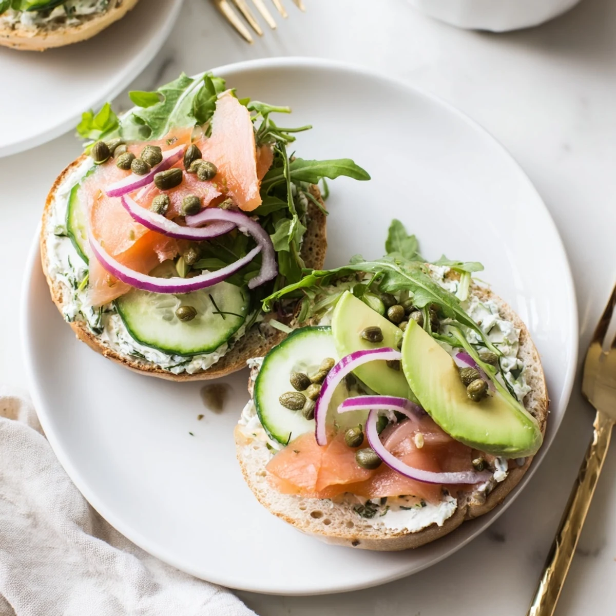 A close-up of a hearty baked salmon brunch bagel, showcasing tender pink salmon flakes, creamy cheese spread, and vibrant green vegetables on a toasted surface.