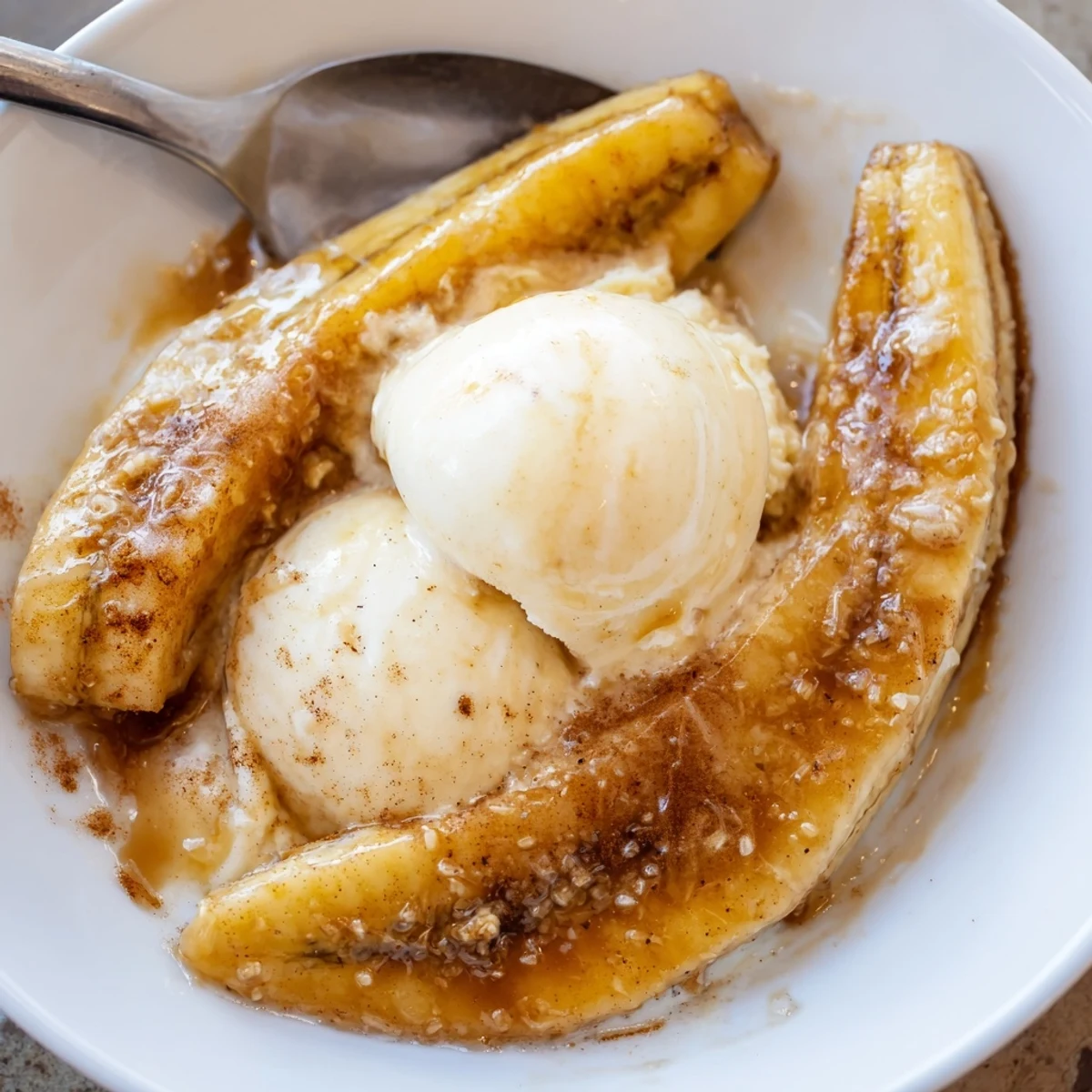 Warm Bananas Foster with caramelized bananas and vanilla ice cream in a serving dish.