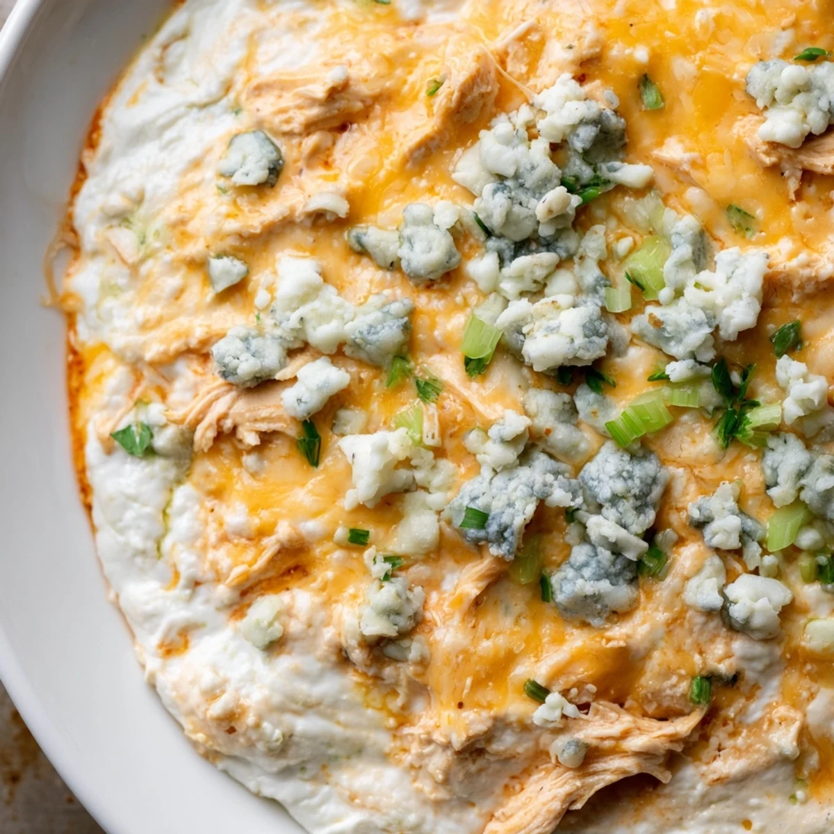 Fresh celery sticks stand ready beside a creamy, golden-baked Spicy Buffalo Chicken Dip, perfect for a game day snack or party appetizer.  