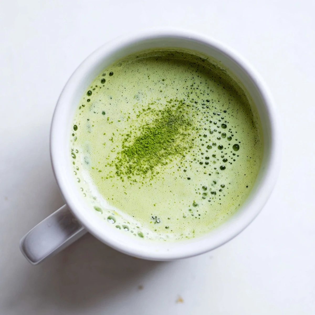 Close-up of frothy matcha latte with oat milk and honey, a vibrant green beverage perfect for an afternoon boost or nourishing break.