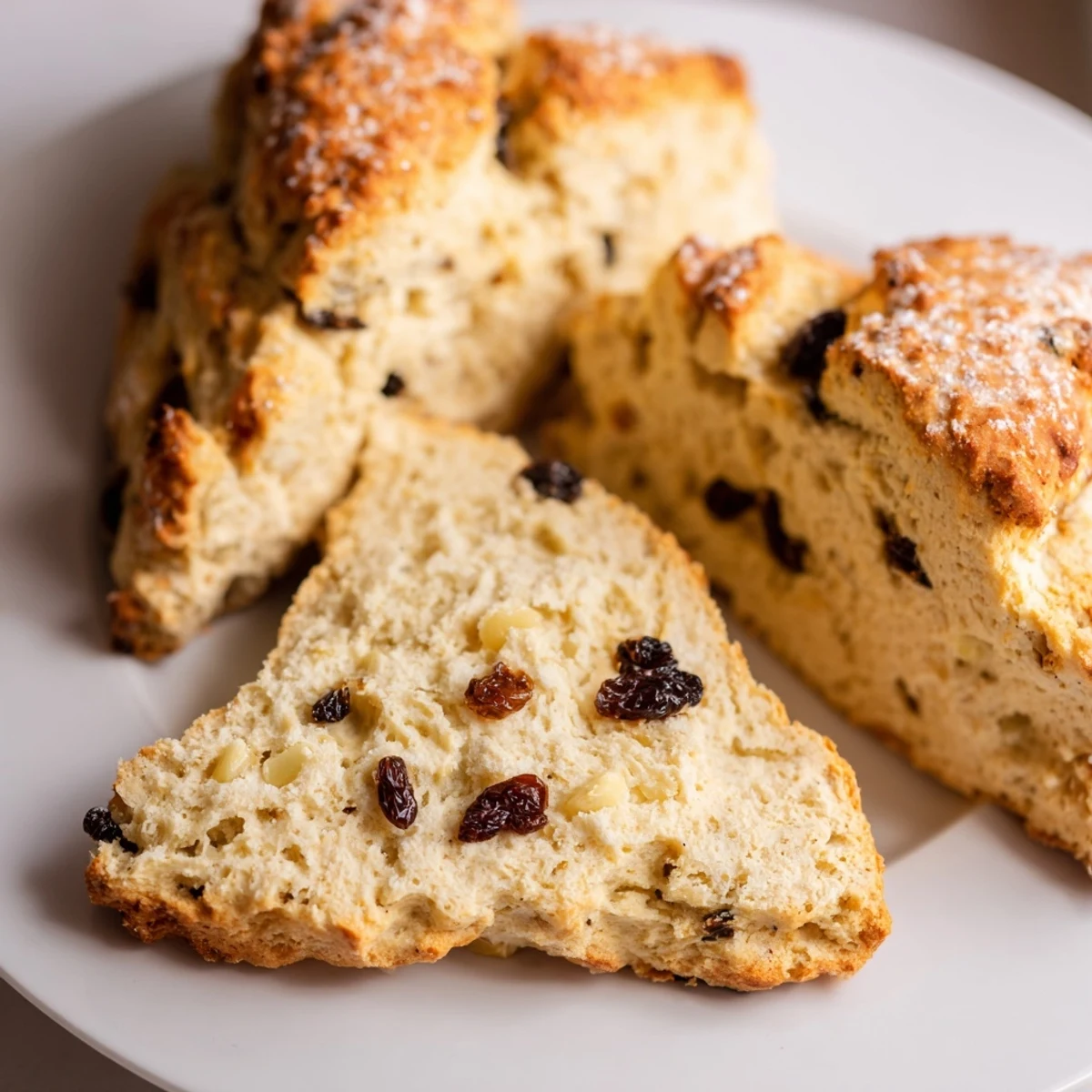 Irish Soda Bread Scones dusted with coarse sugar, showing raisins and caraway seeds on a rustic wooden table.  
