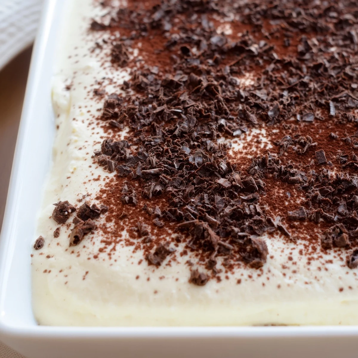This Easy Tiramisu features coffee-soaked ladyfingers nestled between rich layers of mascarpone cream in a clear serving dish.