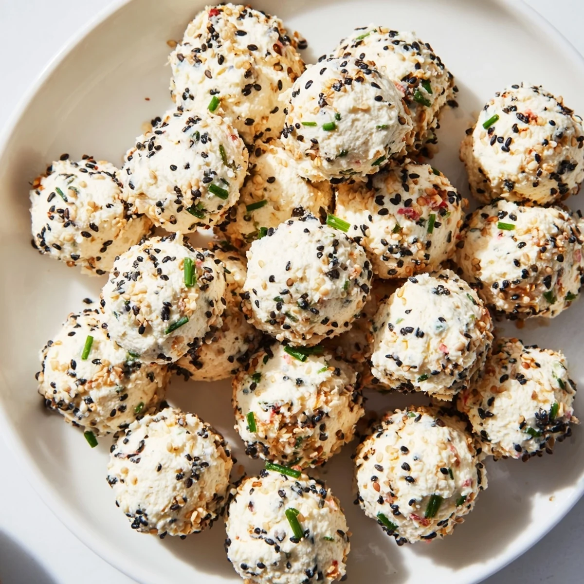 A close-up of creamy Everything Bagel Cottage Cheese Bites garnished with poppy seeds and served with crisp cucumber slices.