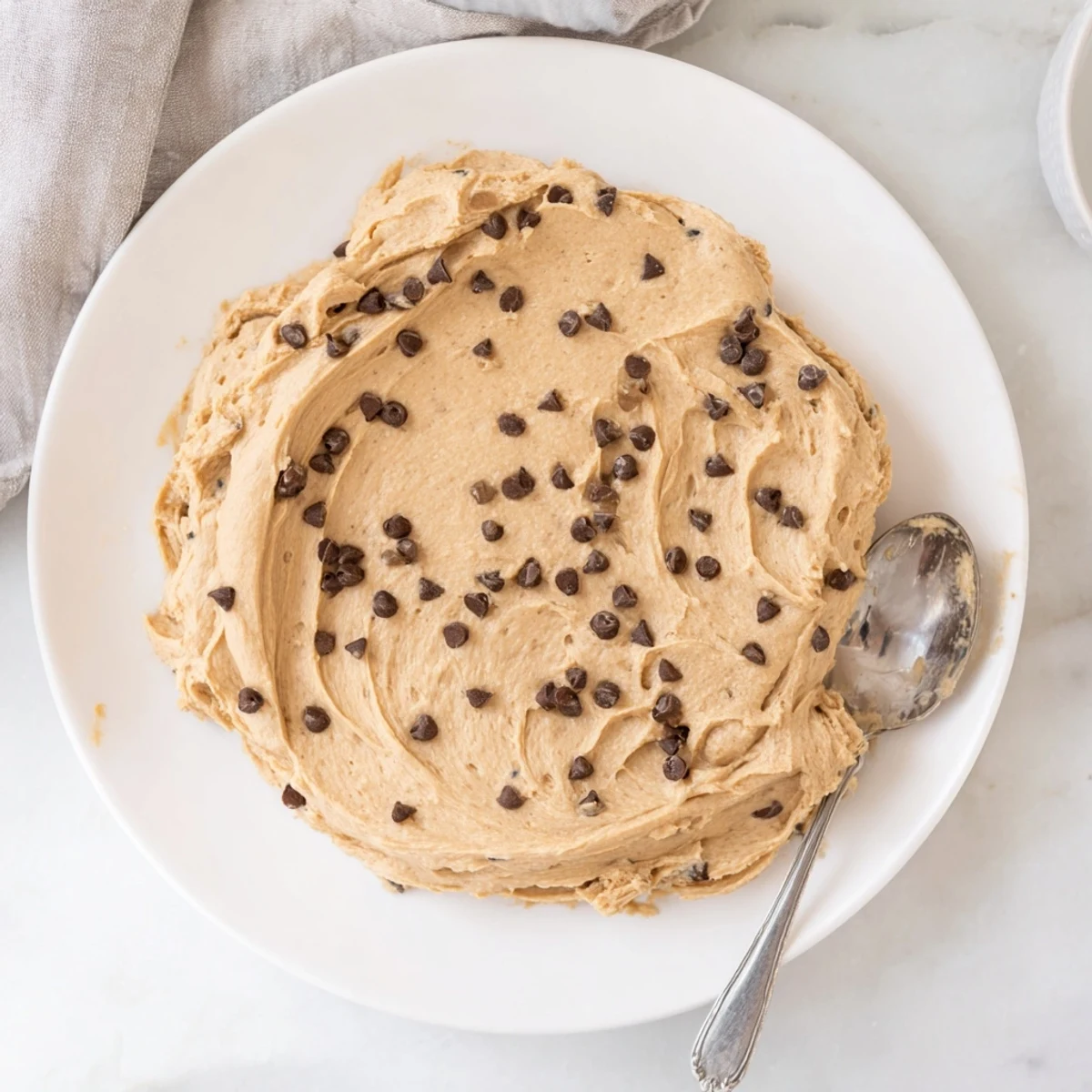 Rich and creamy Cookie Dough Frosting with mini chocolate chips on a vanilla cupcake, ready to serve.