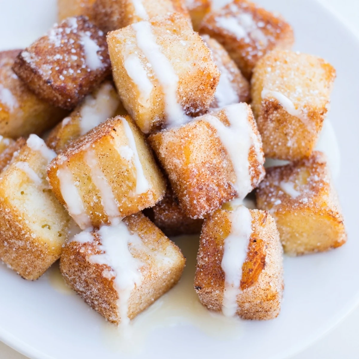 Cinnamon Roll French Toast Bites topped with glaze and maple syrup, perfect for a cozy breakfast.
