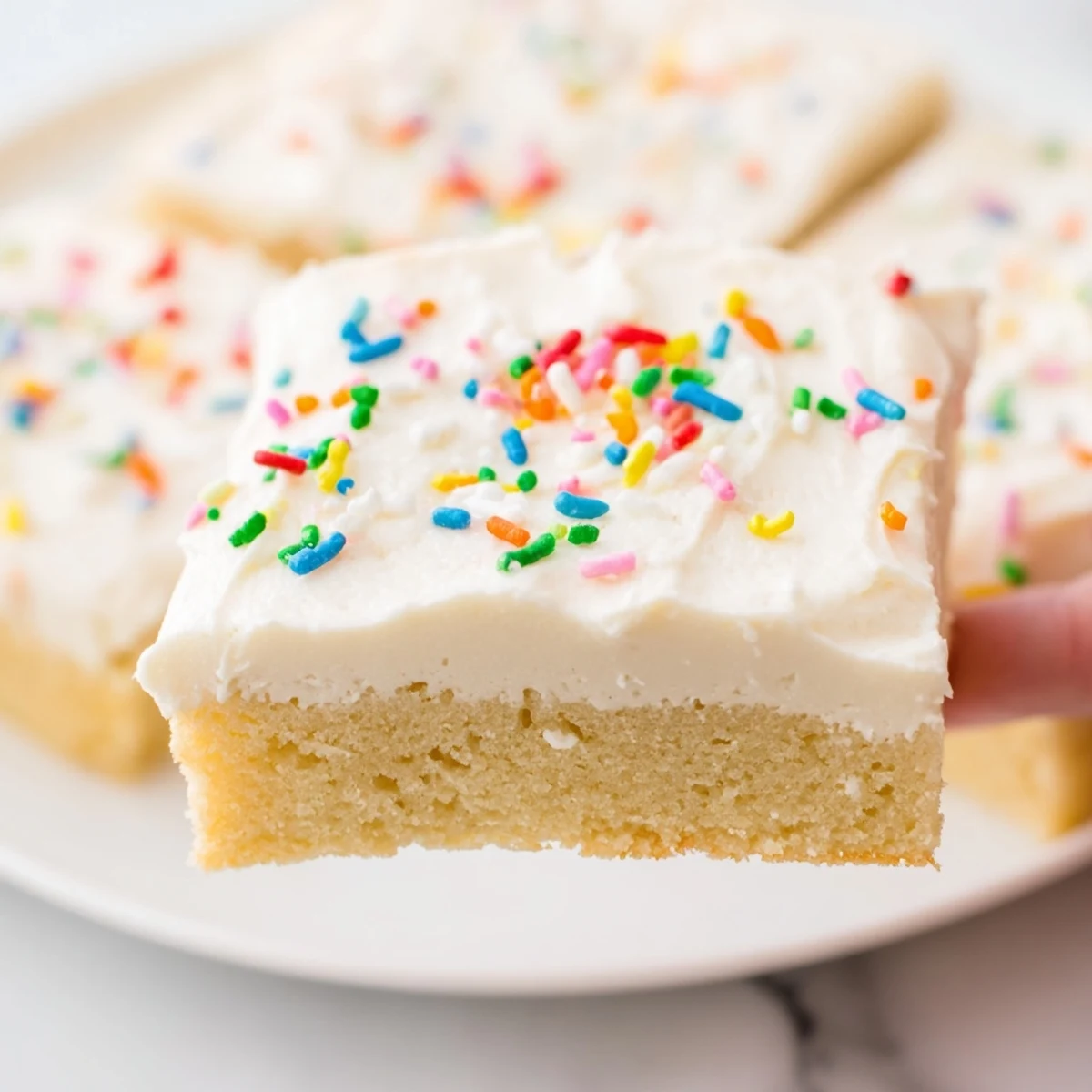 Freshly baked Sugar Cookie Bars with creamy frosting and colorful sprinkles on a festive plate.