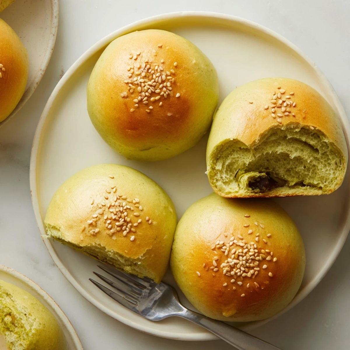 Warm, soft Matcha Red Bean Buns served with tea on a cozy breakfast plate.