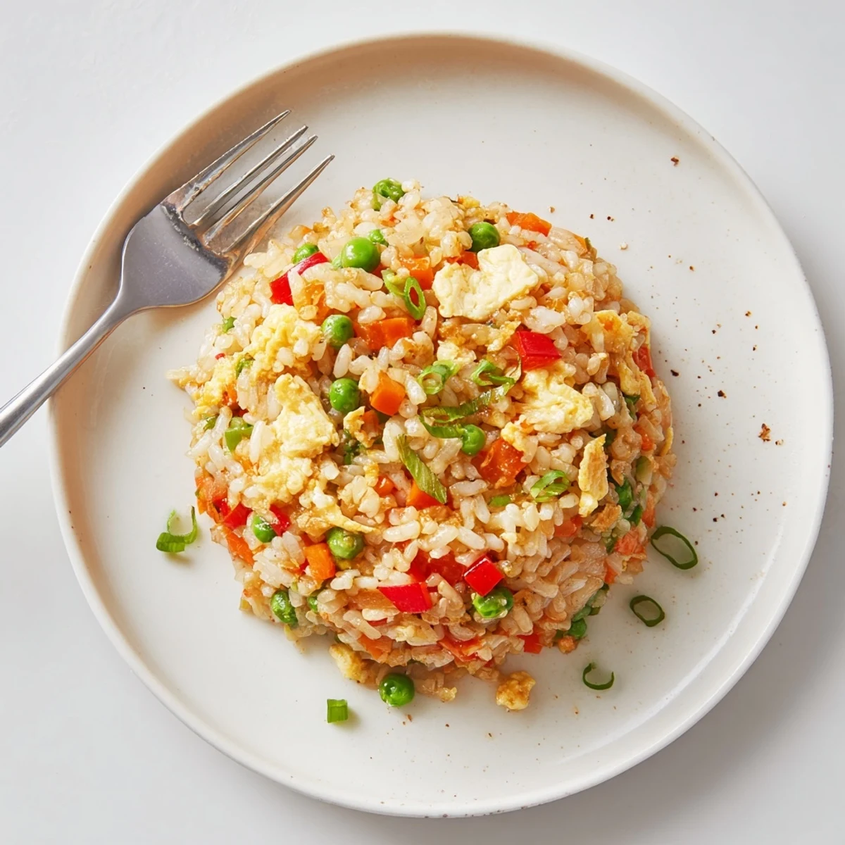 Steaming Fried Rice in a wok with peas, carrots, and scrambled eggs, served in a bowl.