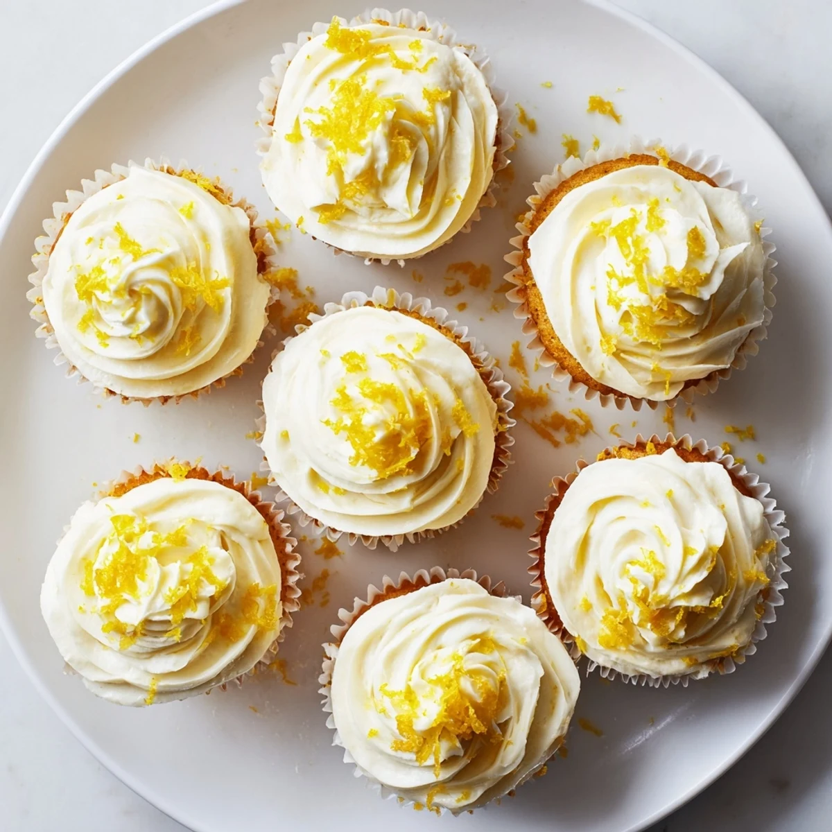 Golden Limoncello Cupcakes are brushed with syrup and topped with creamy frosting on a summer dessert table.