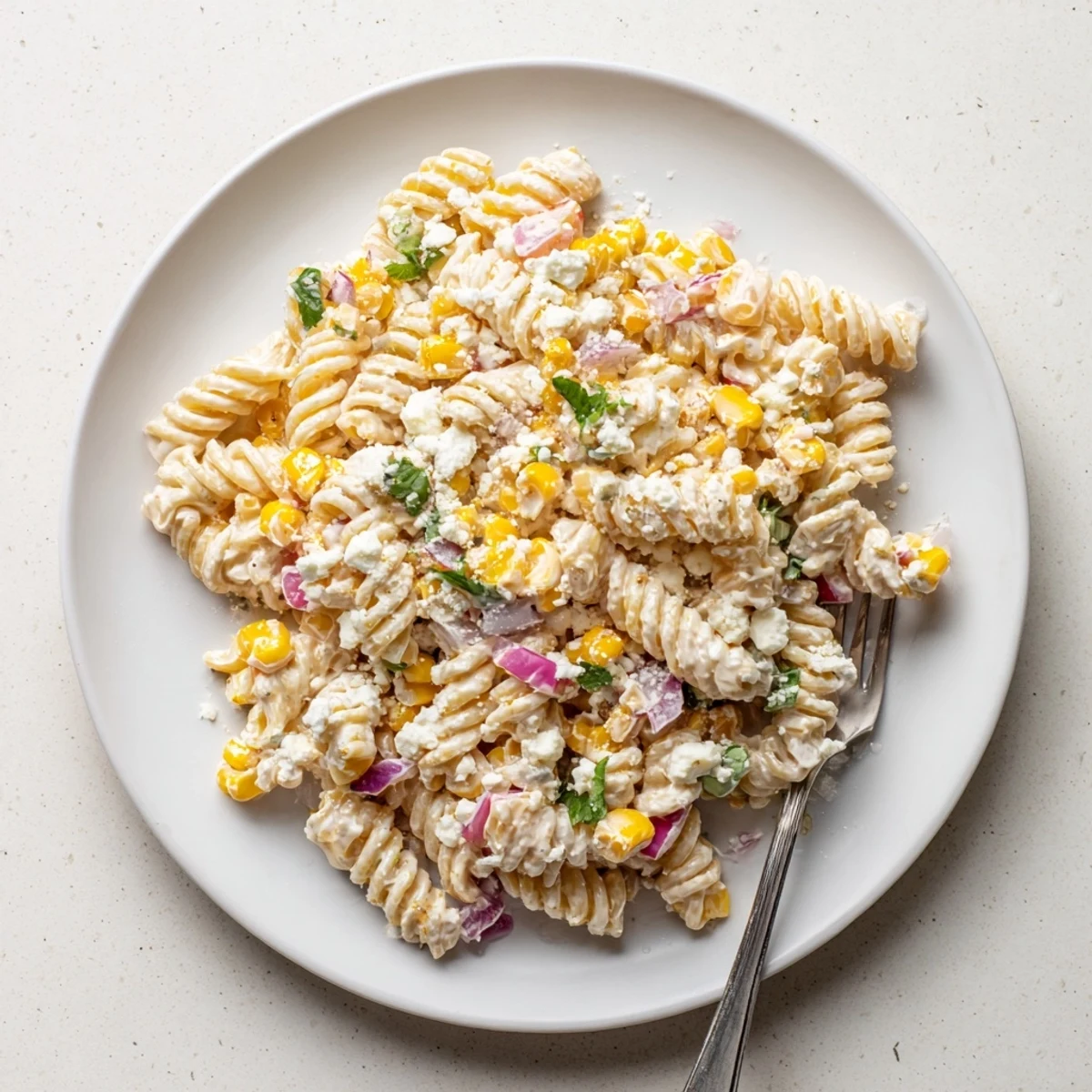 Zesty Mexican street corn pasta salad featuring charred corn kernels and tangy feta in a creamy sauce