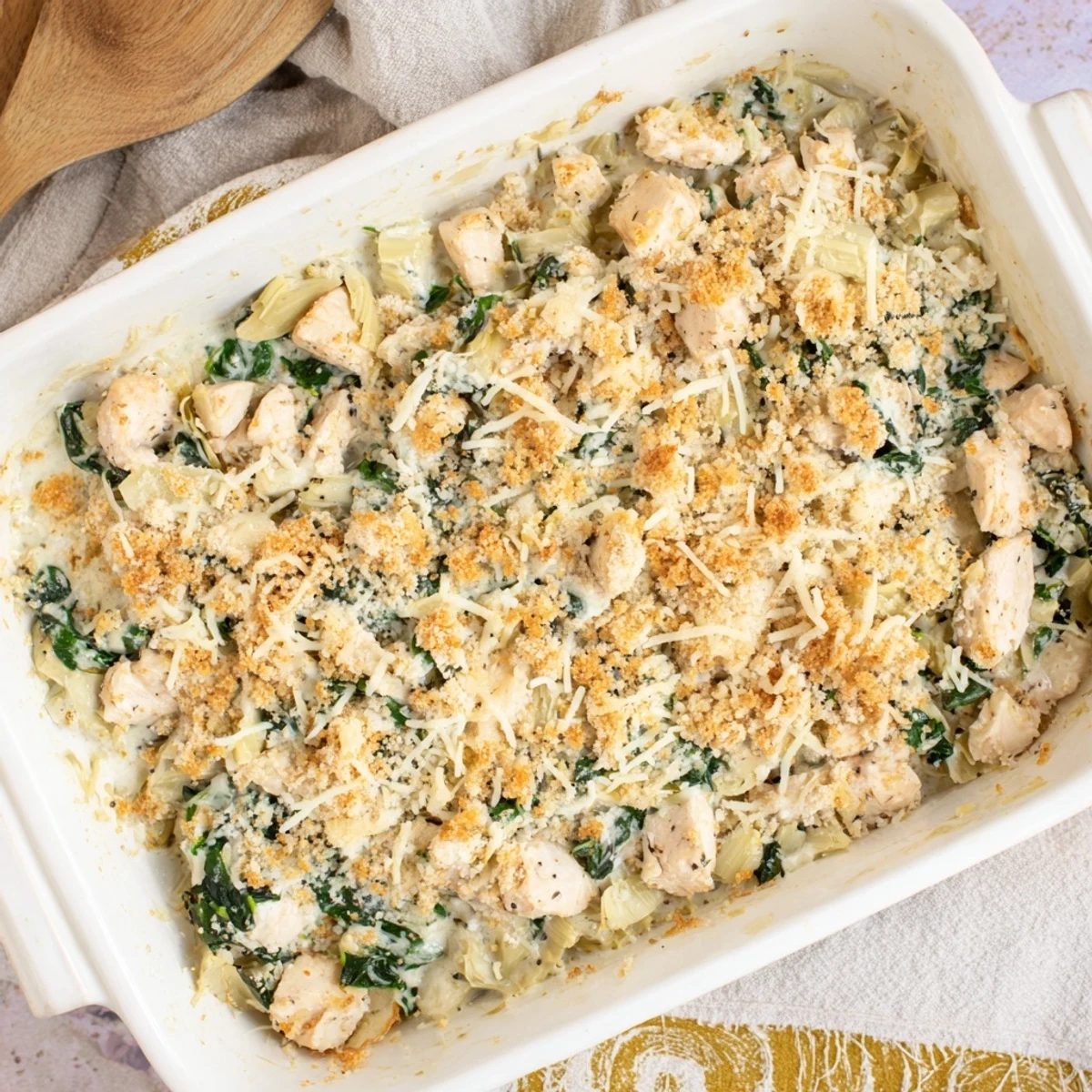 Scoop of cheesy spinach and artichoke chicken casserole served with fresh parsley garnish