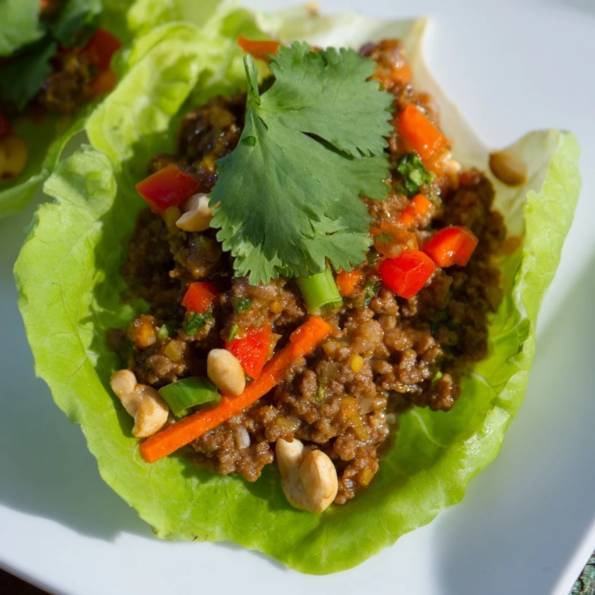 Golden brown beef and cashew mixture spooned into cool butter lettuce leaves topped with cilantro and lime wedges