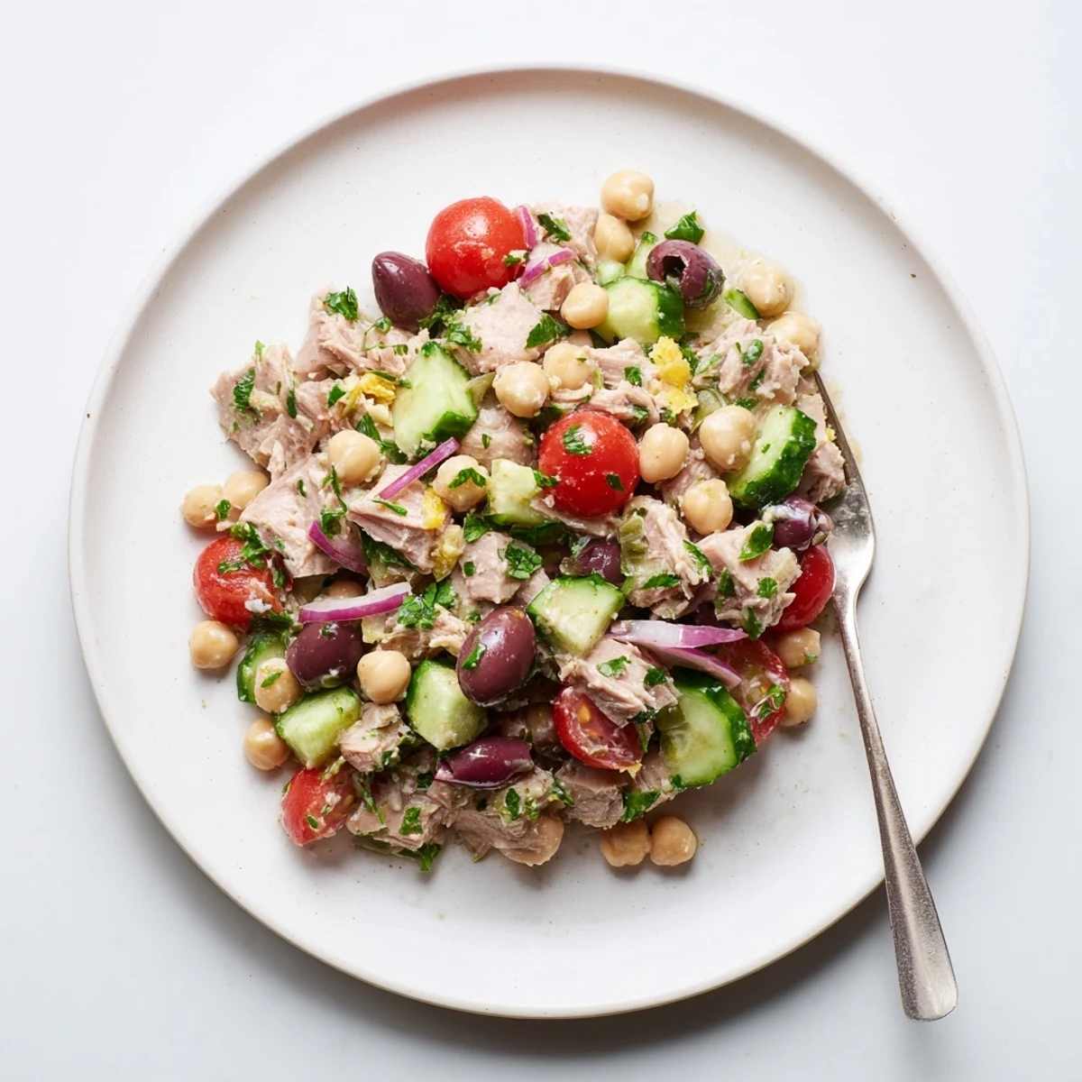 Colorful hearty tuna and garbanzo bean salad featuring fresh vegetables and zesty lemon-herb dressing in a white bowl