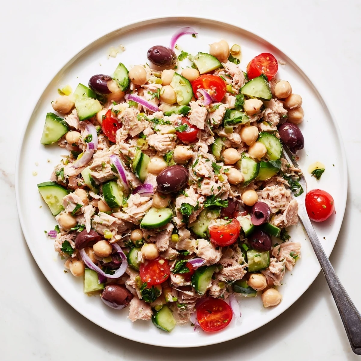 Mediterranean-style hearty tuna and garbanzo bean salad topped with cherry tomatoes, cucumber, and olives for a protein-packed lunch