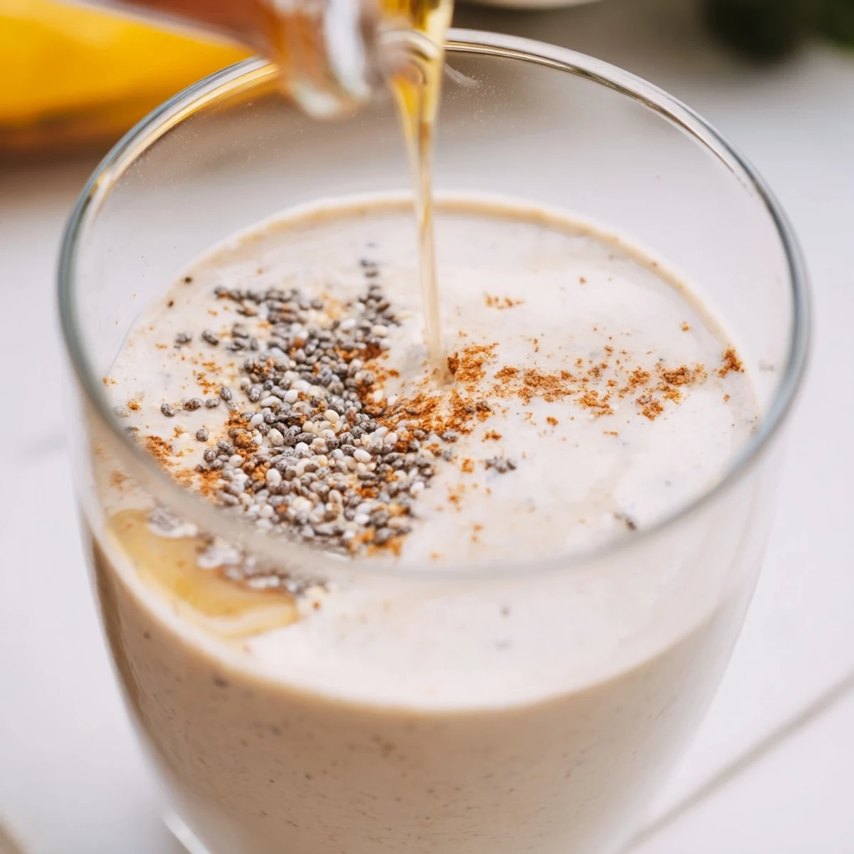 Creamy Greek yogurt banana smoothie poured into a tall glass with visible ice cubes