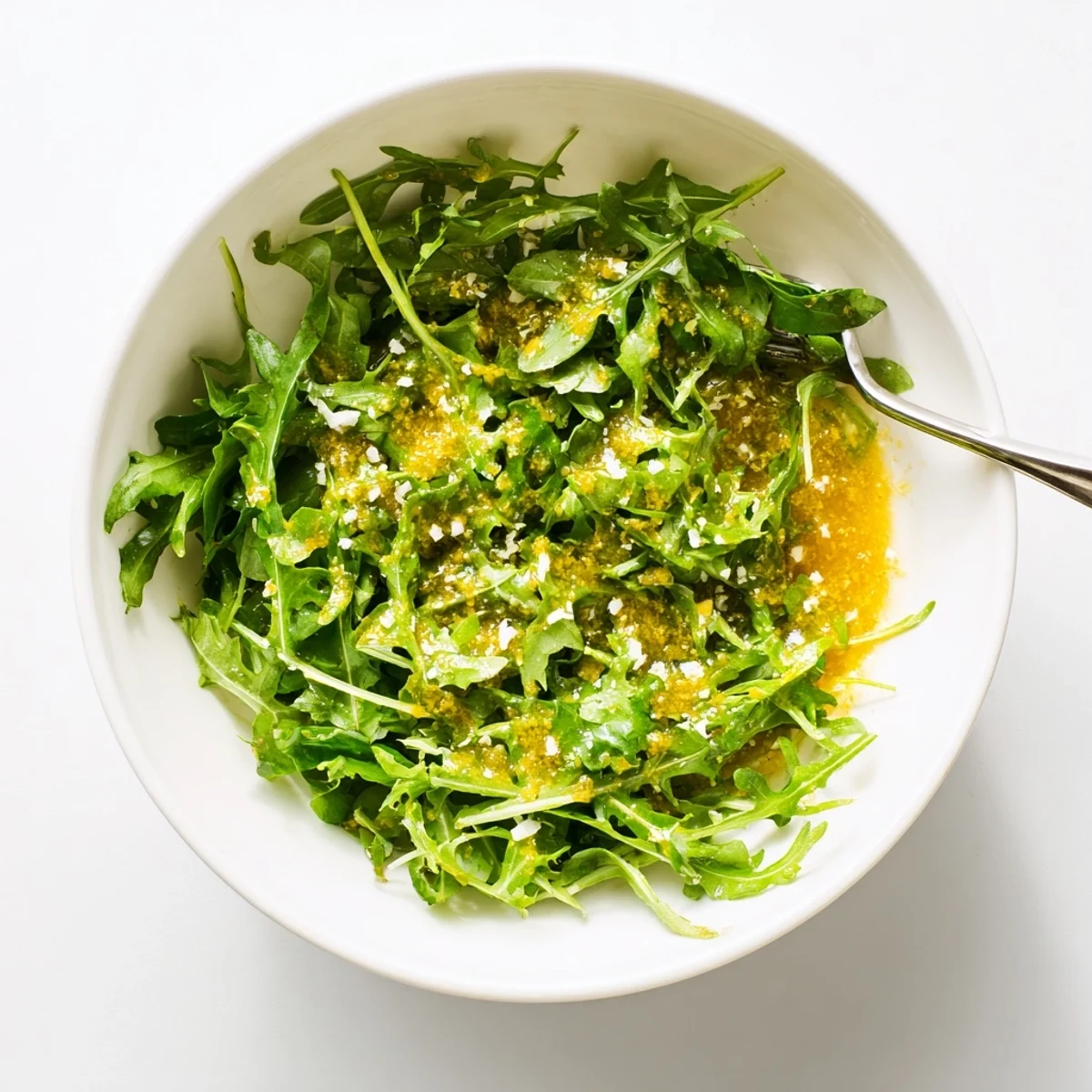 Golden honey lemon vinaigrette dressing drizzled over fresh mixed green salad in white bowl