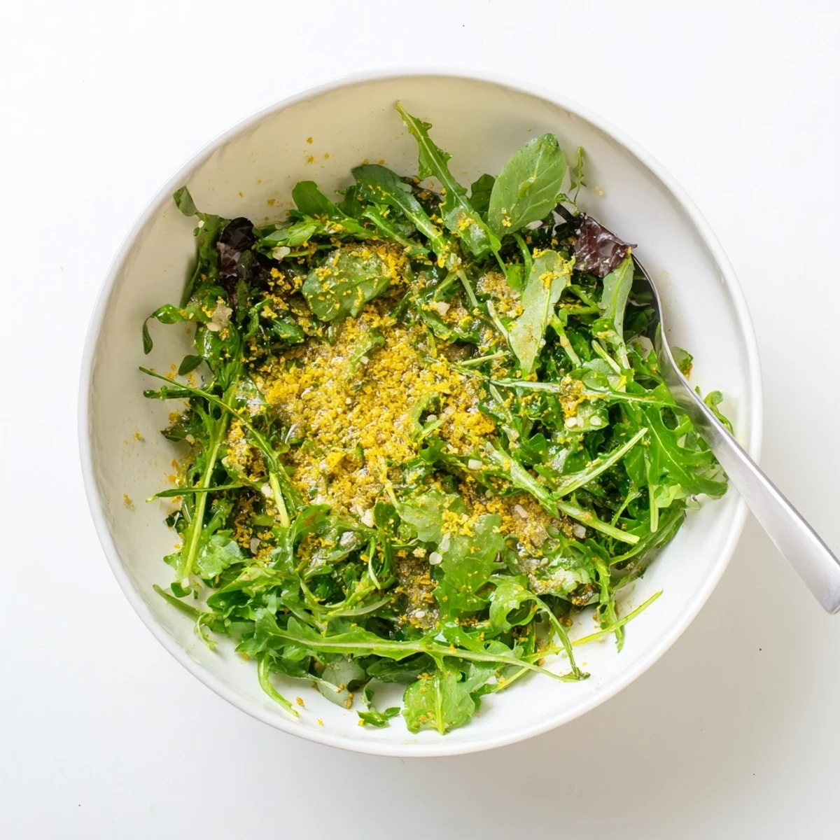 Tangy honey lemon vinaigrette poured from spoon onto crisp garden salad with colorful vegetables