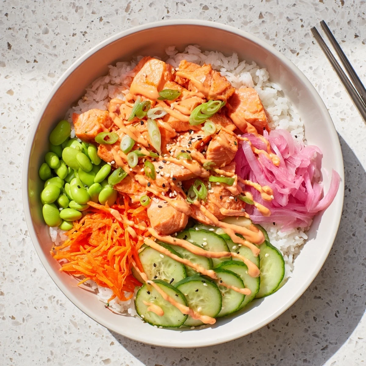 Flaky baked salmon served over fluffy rice with crisp vegetables and spicy mayo drizzle