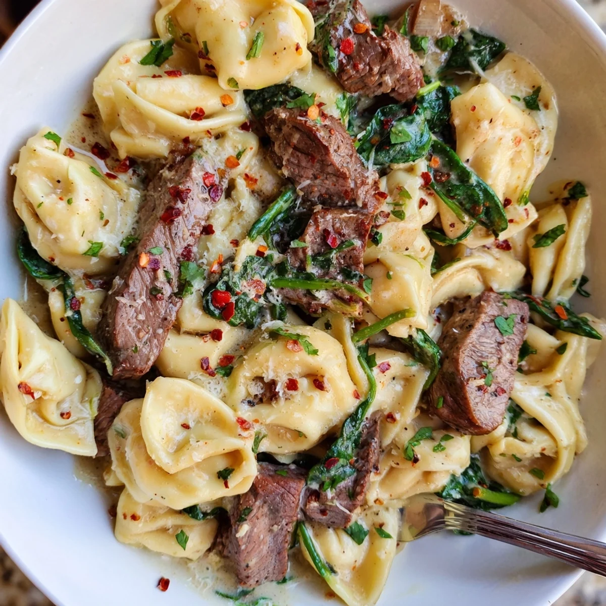 Golden seared beef strips and cheese tortellini swirl in a rich garlic cream sauce