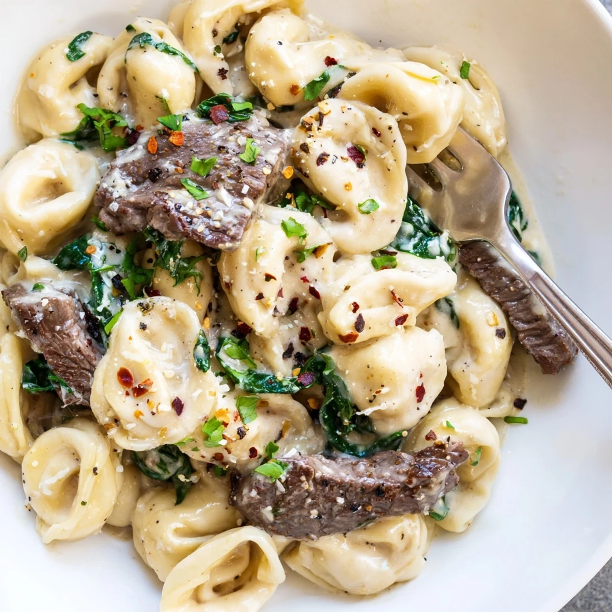 Creamy garlic steak tortellini dish featuring tender beef pieces and wilted spinach in white sauce