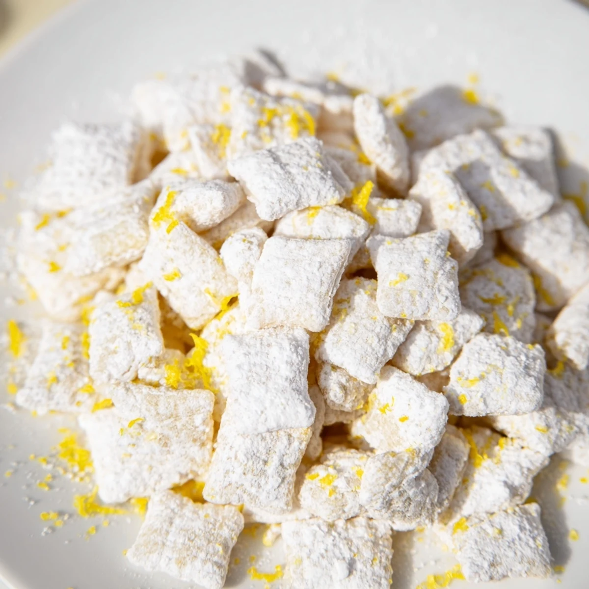 Bowl of zesty Lemonade Puppy Chow featuring lemon-infused white chocolate coating and sugary powdered finish on crispy rice cereal squares