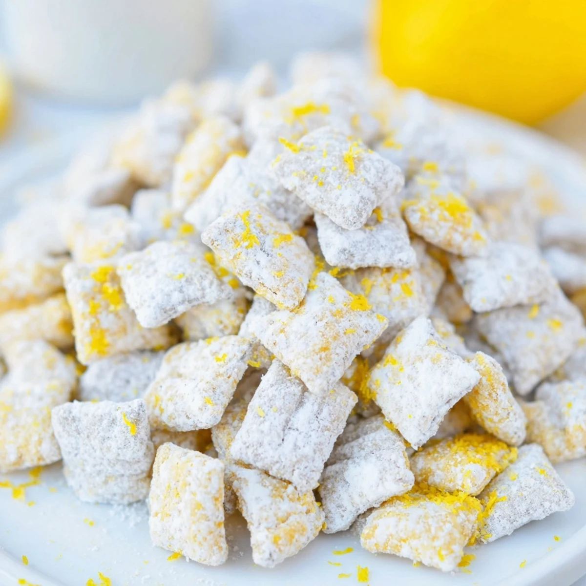 Close-up of Lemonade Puppy Chow snack mix with lemon glazed cereal pieces scattered on a white baking sheet