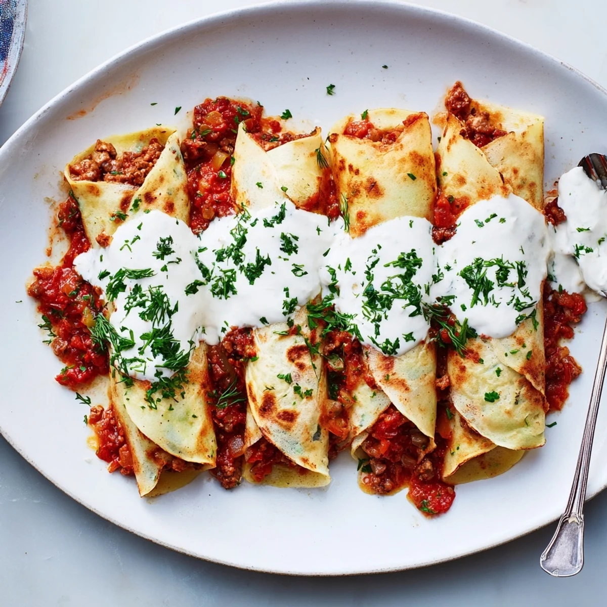 Golden Hungarian Hortobágyi palacsinta rolled with savory paprika meat filling and creamy sour cream sauce bubbling hot from baking