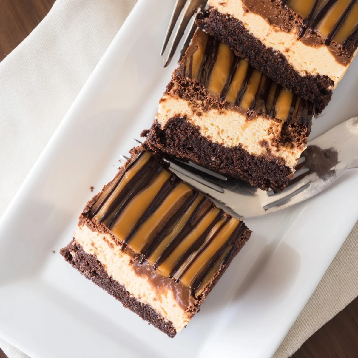 Slice of caramel brownie cheesecake bliss showing swirled chocolate cheesecake layers with glossy caramel sauce