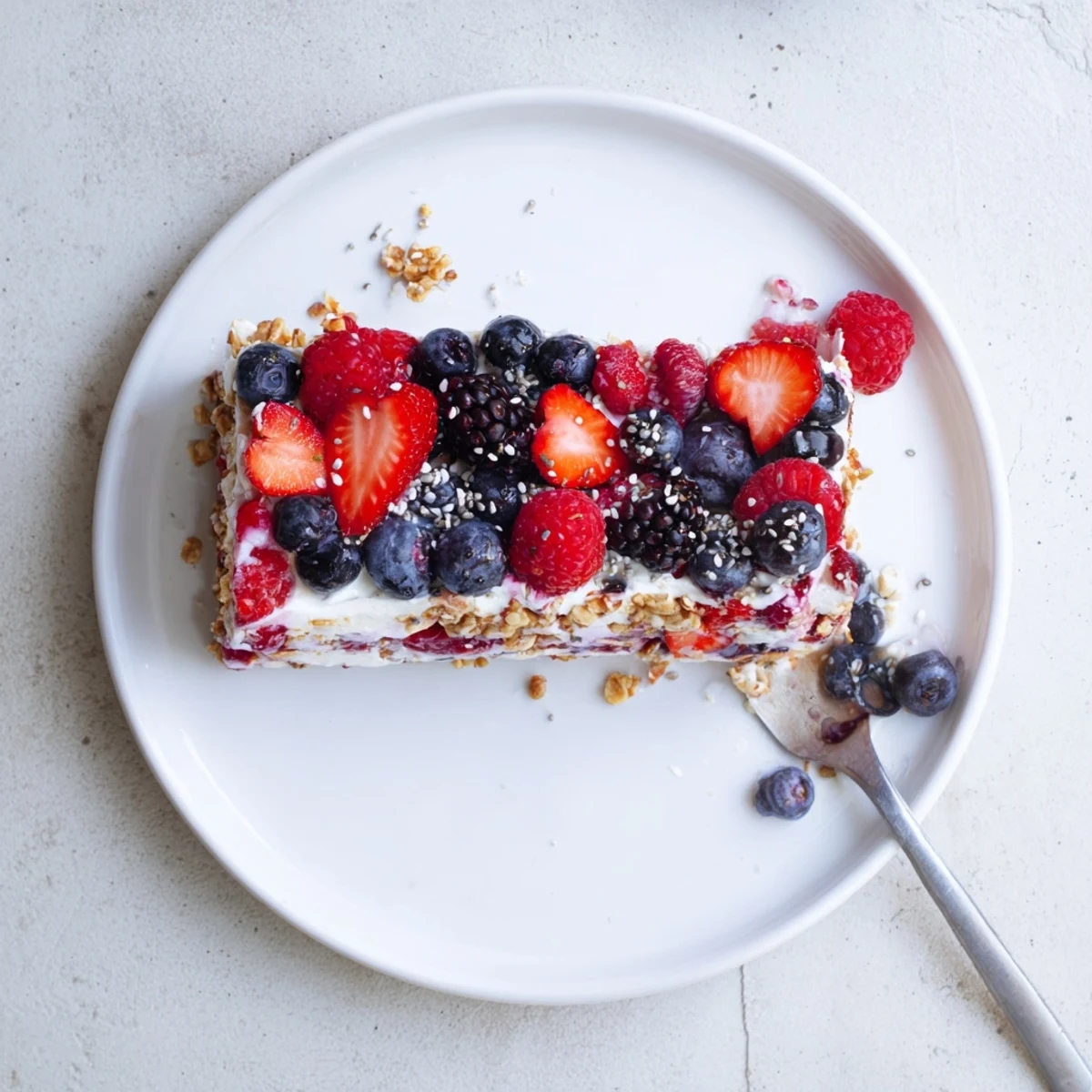 Creamy Greek yogurt frozen berry bars topped with colorful mixed fruit and honey-sweetened granola crust
