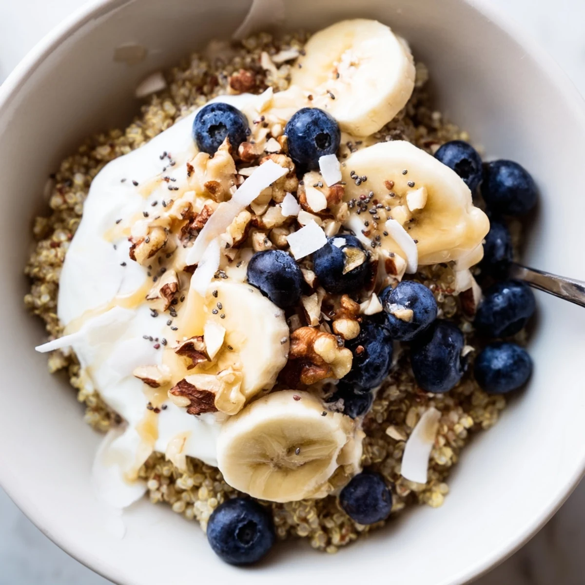 Vibrant blueberry quinoa bowl drizzled with honey and garnished with almond slices and coconut