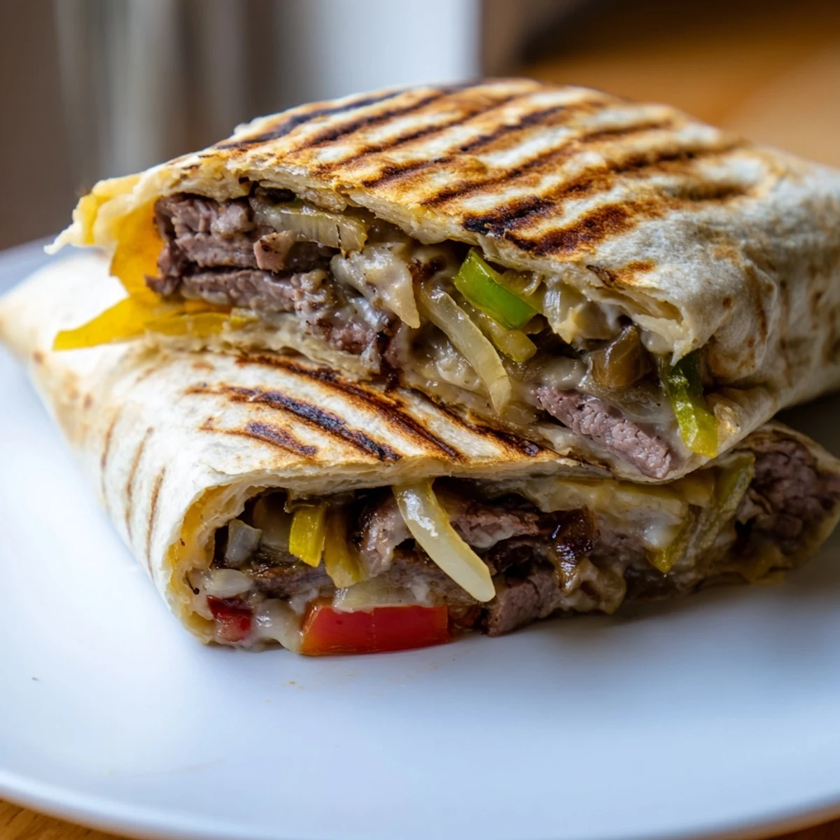 Golden crispy Philly cheesesteak grilled wraps with melted cheese and colorful peppers