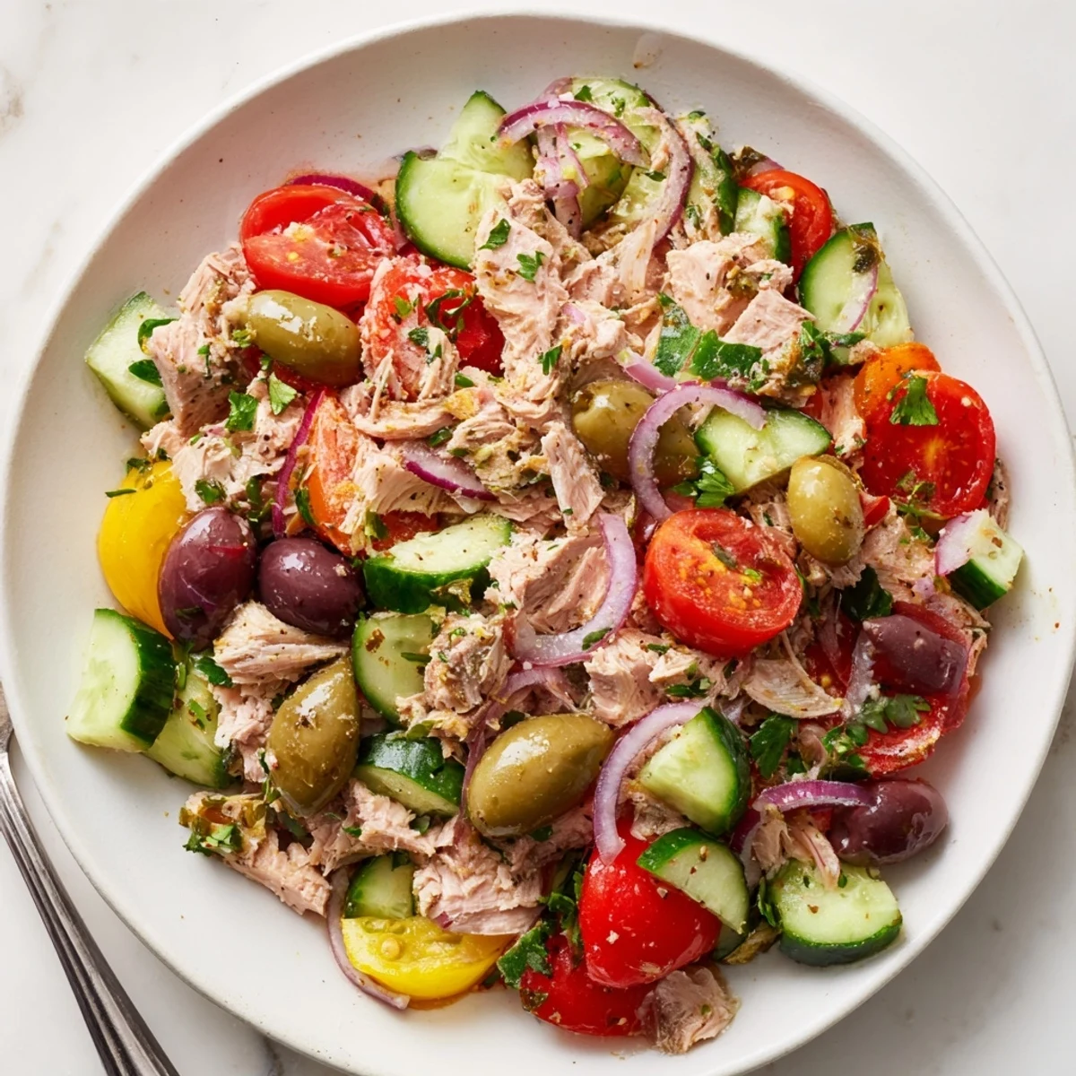 Simple Mediterranean Tuna Salad in a bright white bowl with cherry tomatoes and olives scattered on top