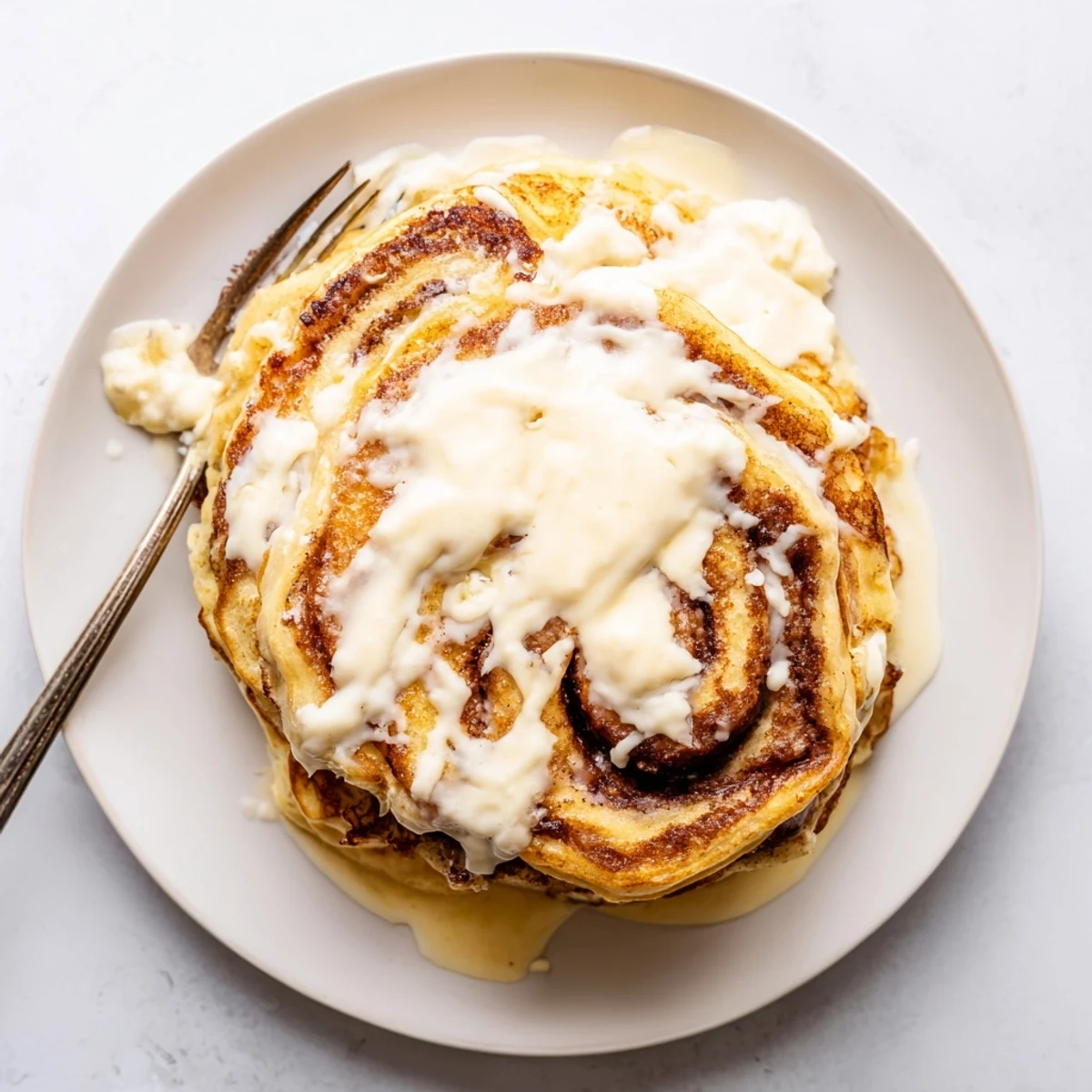 Fluffy pancakes spiraled with warm cinnamon sugar filling on a white plate