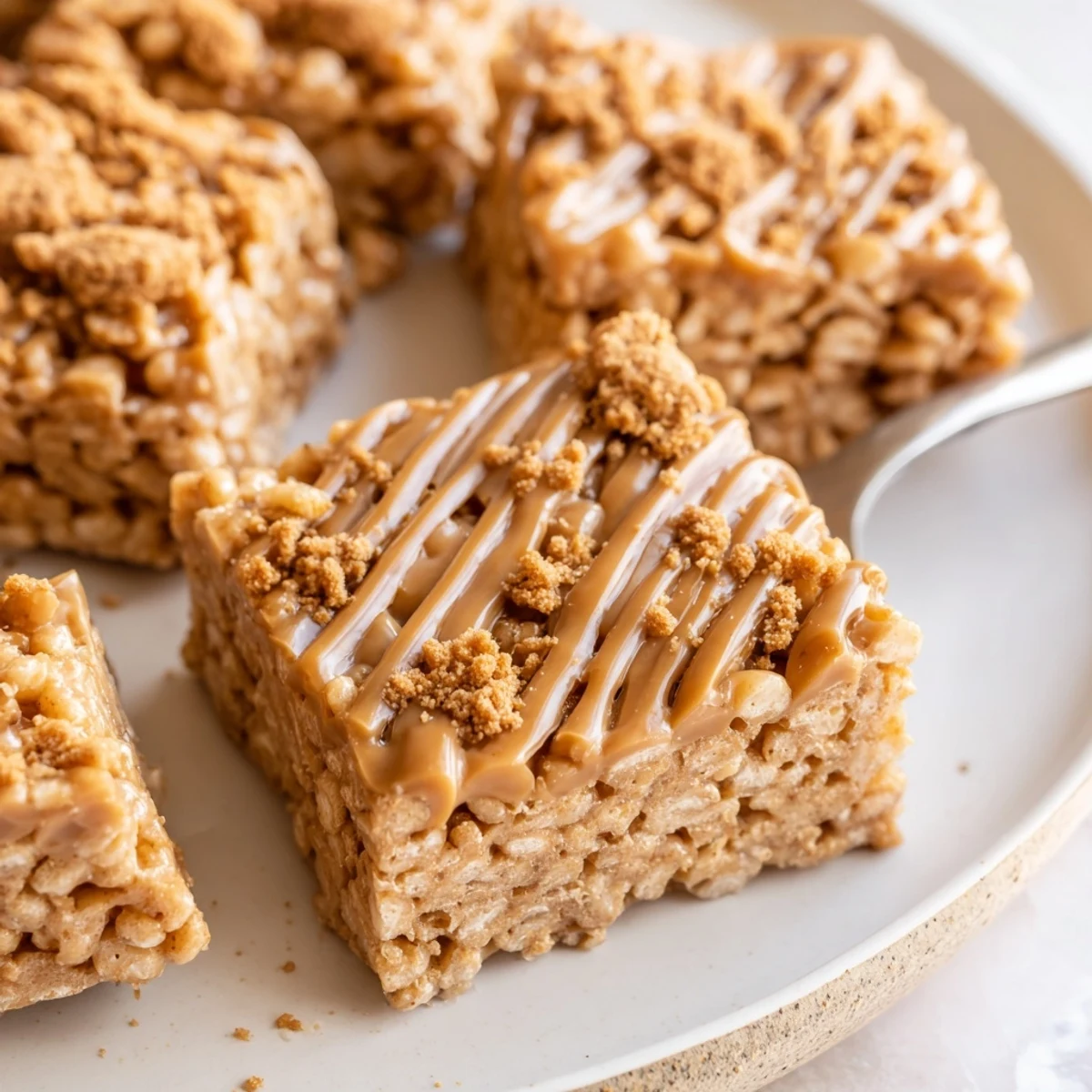 Biscoff Rice Krispie Treats with glossy drizzle, golden edges, sticky marshmallow center