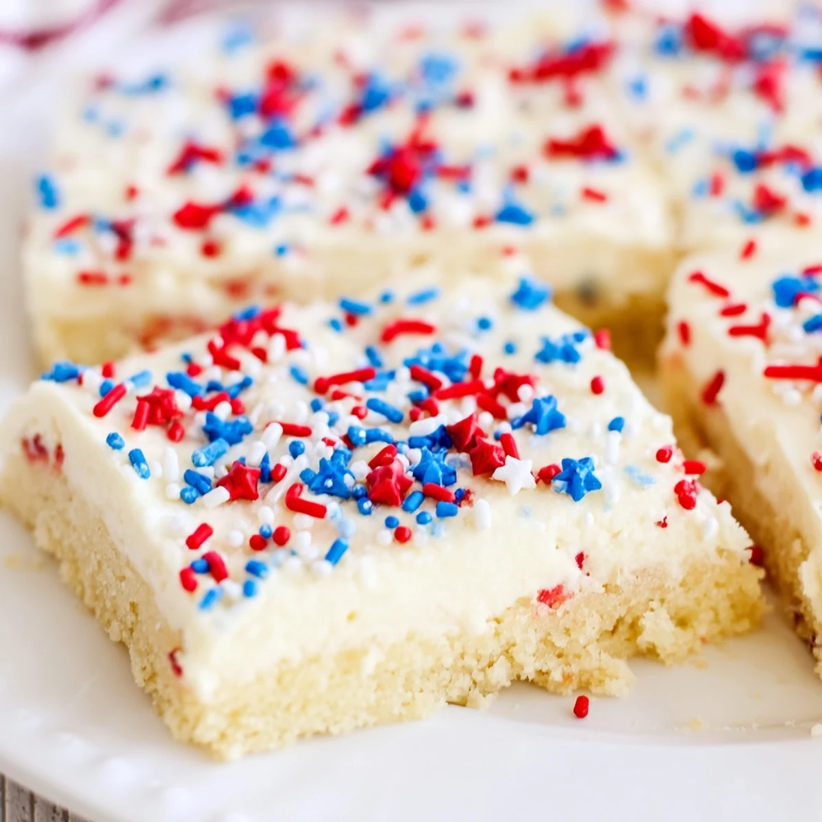 Patriotic sugar cookie bars with fluffy vanilla frosting and festive sprinkles, perfect for summer Fourth of July celebrations and parties