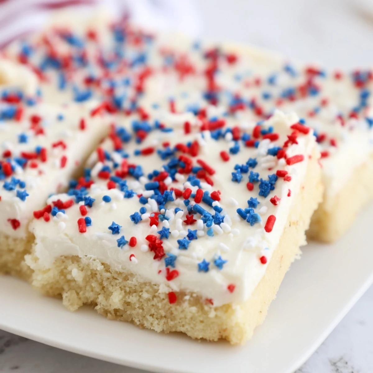 Soft 4th of July sugar cookie bars topped with creamy white frosting and colorful red white blue sprinkles for Independence Day