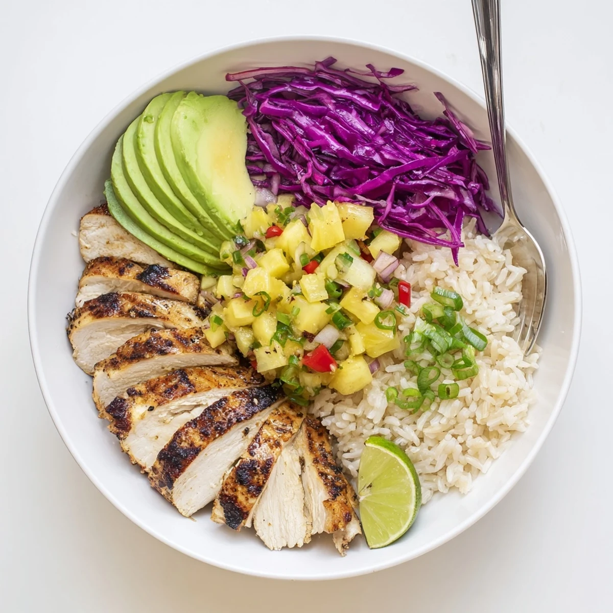 Spicy-sweet Jerk Chicken Bowl With Pineapple Salsa, tangy lime wedge and red cabbage.