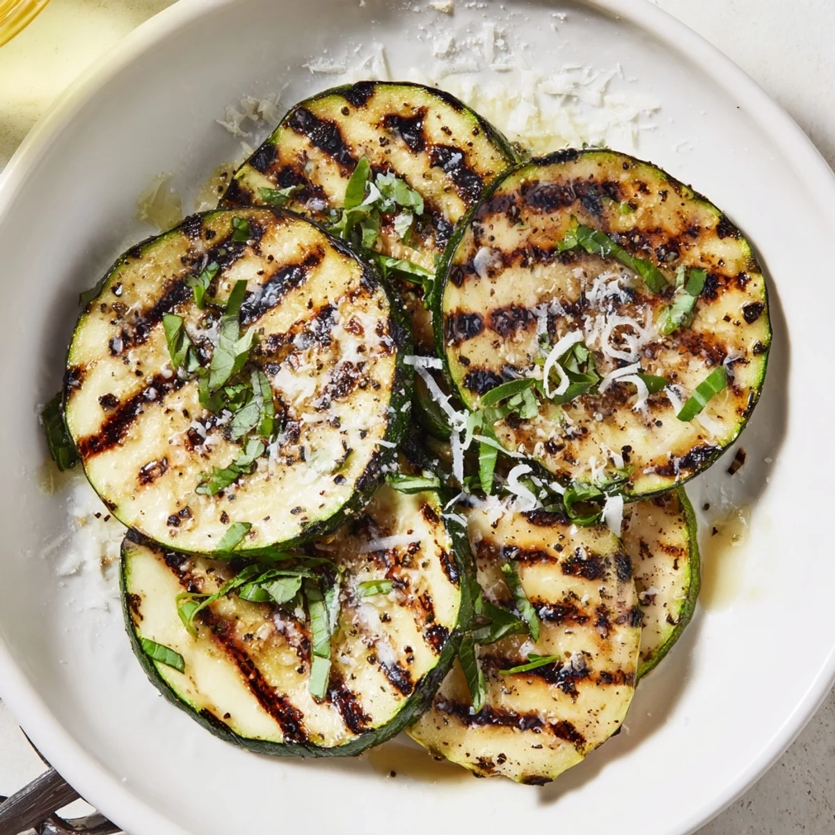Charred, tender slices on platter: Crispy Grilled Zucchini With Parmesan And Fresh Herbs