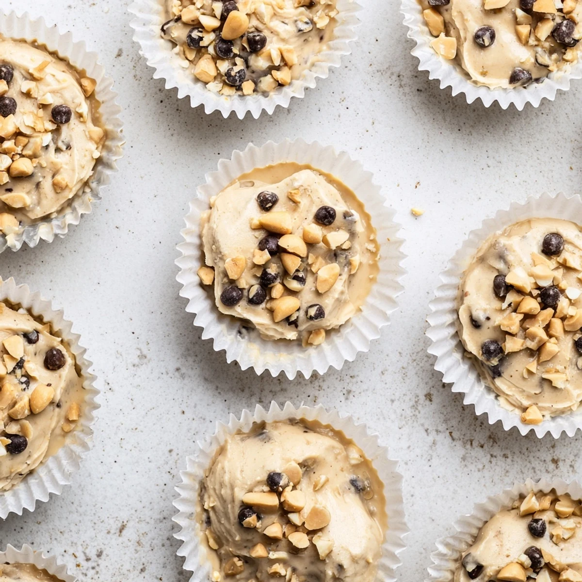 Frozen peanut butter Greek yogurt bites arranged in a muffin tin with chocolate chip and peanut toppings