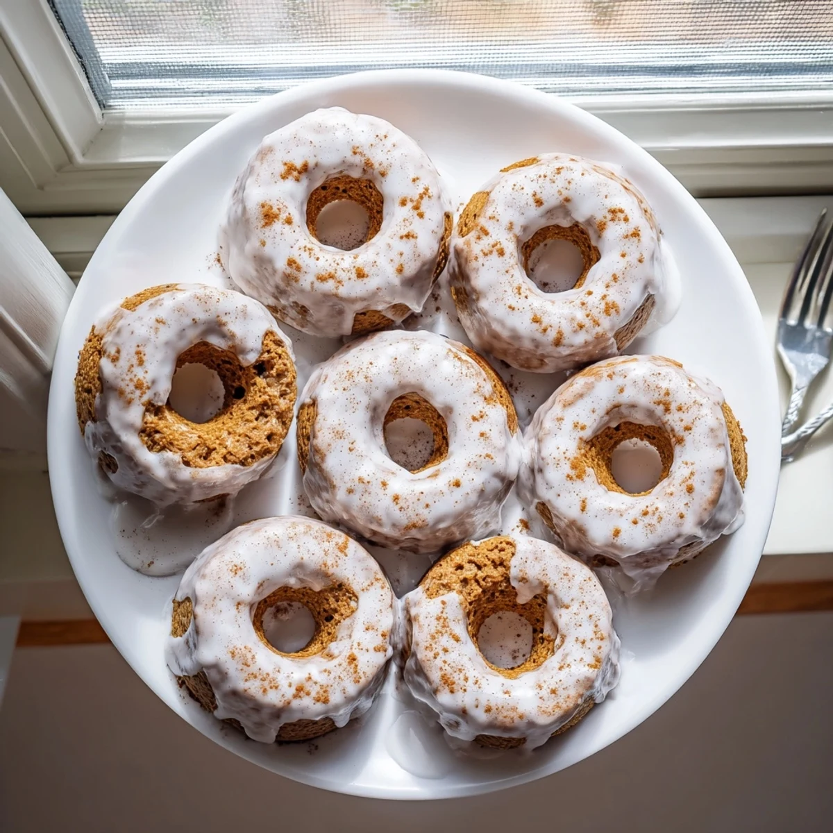 Moist banana bread donuts topped with sweet vanilla glaze and served on a white plate