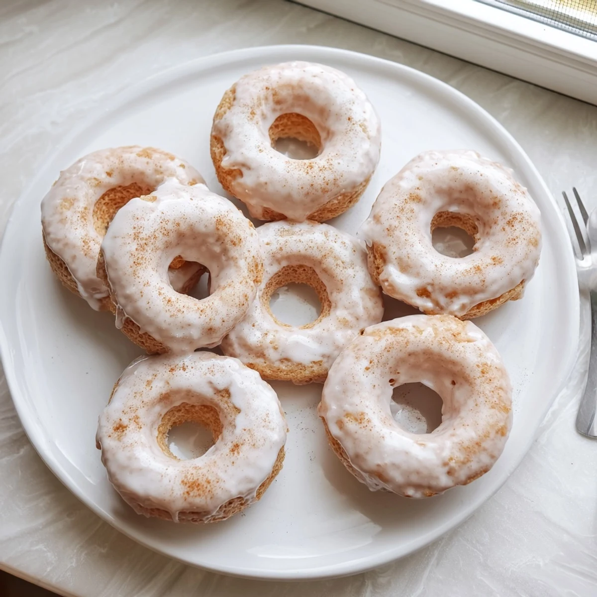 Golden glazed banana bread donuts cooling on a wire rack with powdered sugar dusting