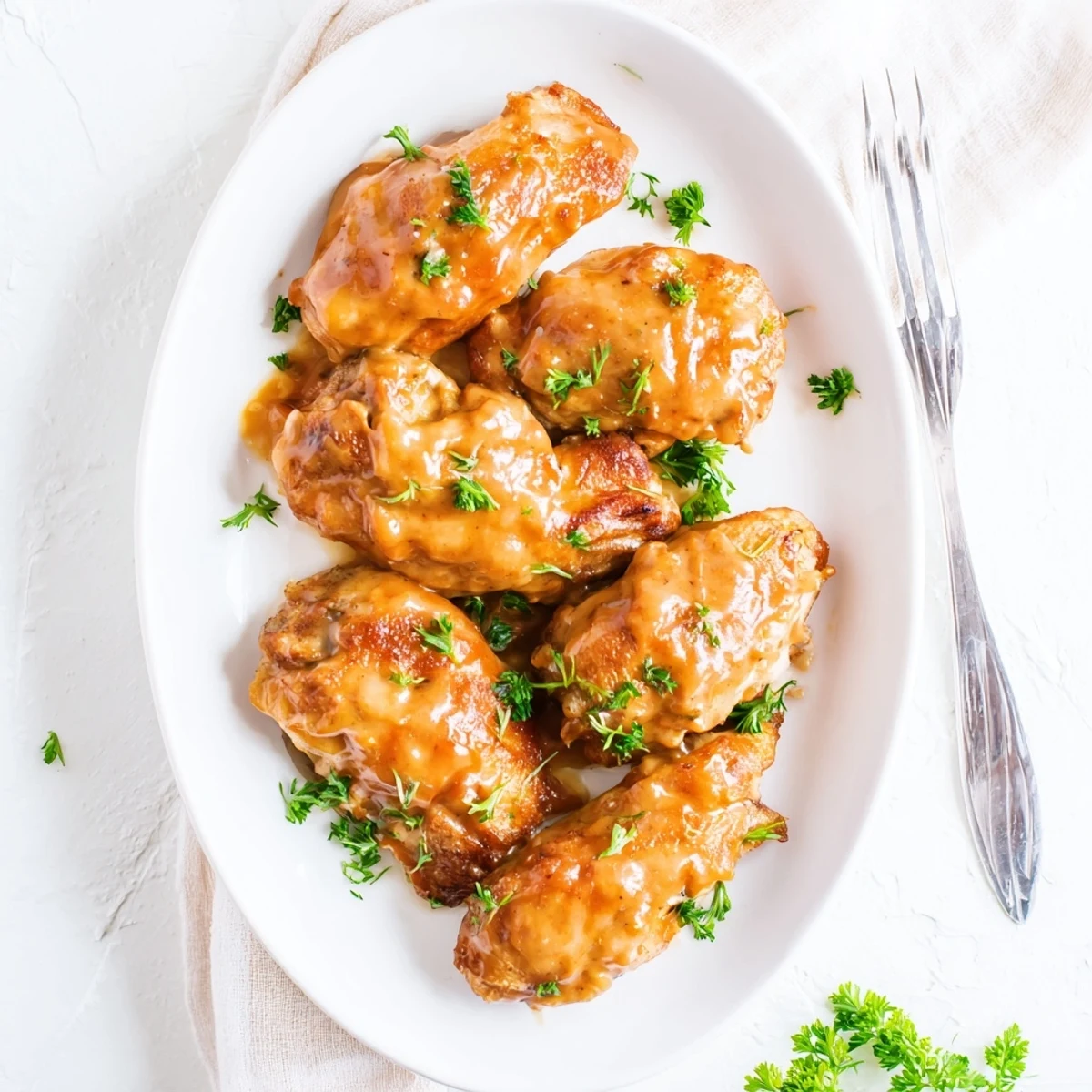 Juicy baked honey mustard chicken pieces coated in caramelized honey dijon sauce on a white serving platter